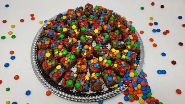 A plate of chocolate fudge covered with m & ms.