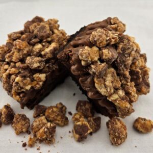 Two chocolate brownies topped with nuts.