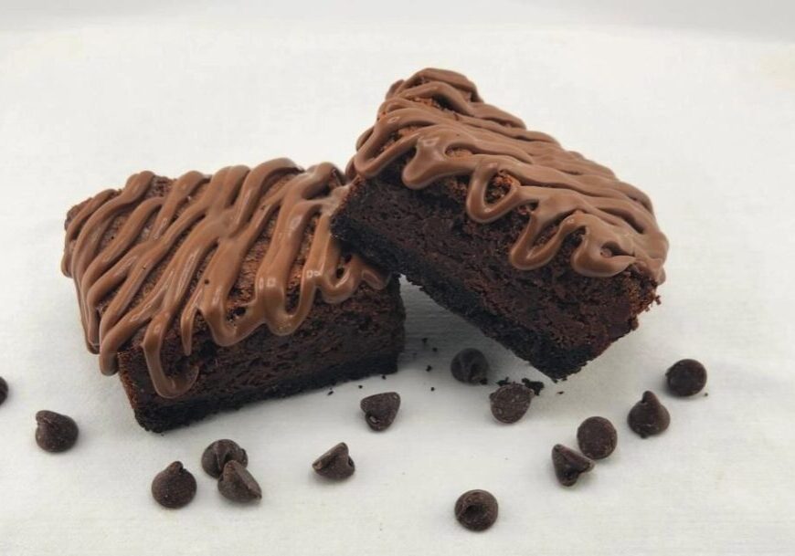 Two brownies with chocolate frosting and chocolate chips.