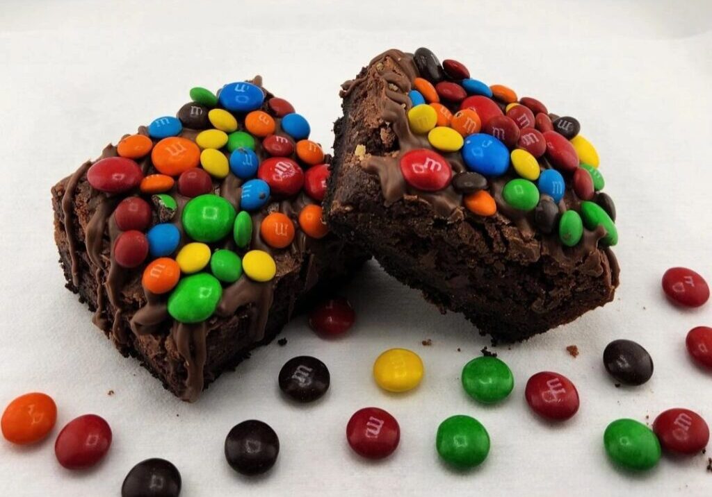 A close up of two brownies with candy on top